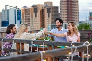 groupe-adultes-amis-terrasse-trinquer-heureux sur un toit